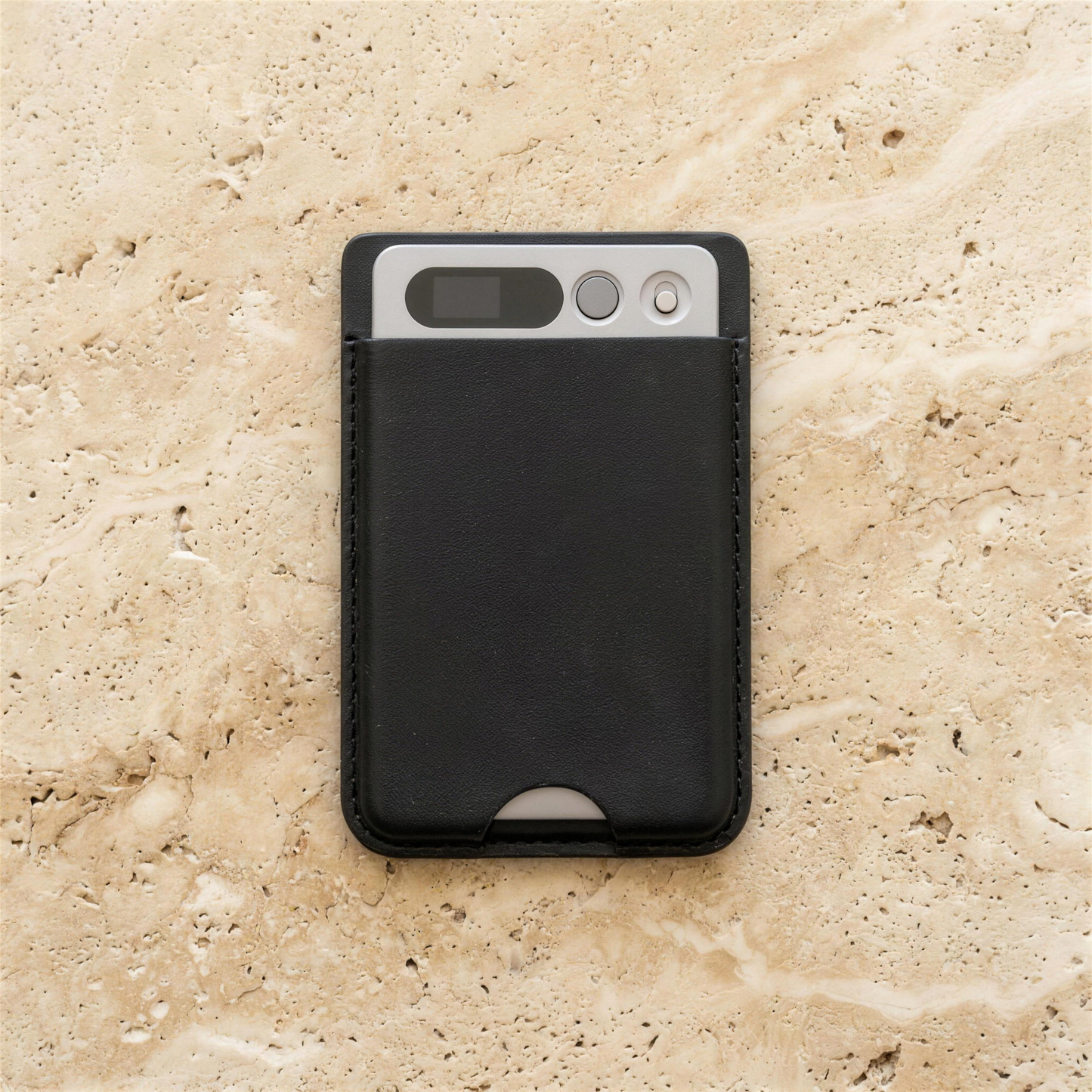 notu R1 Pro in its black leather MagSafe wallet lying on travertine stone — display window, record button and microphone visible on the aluminum top edge